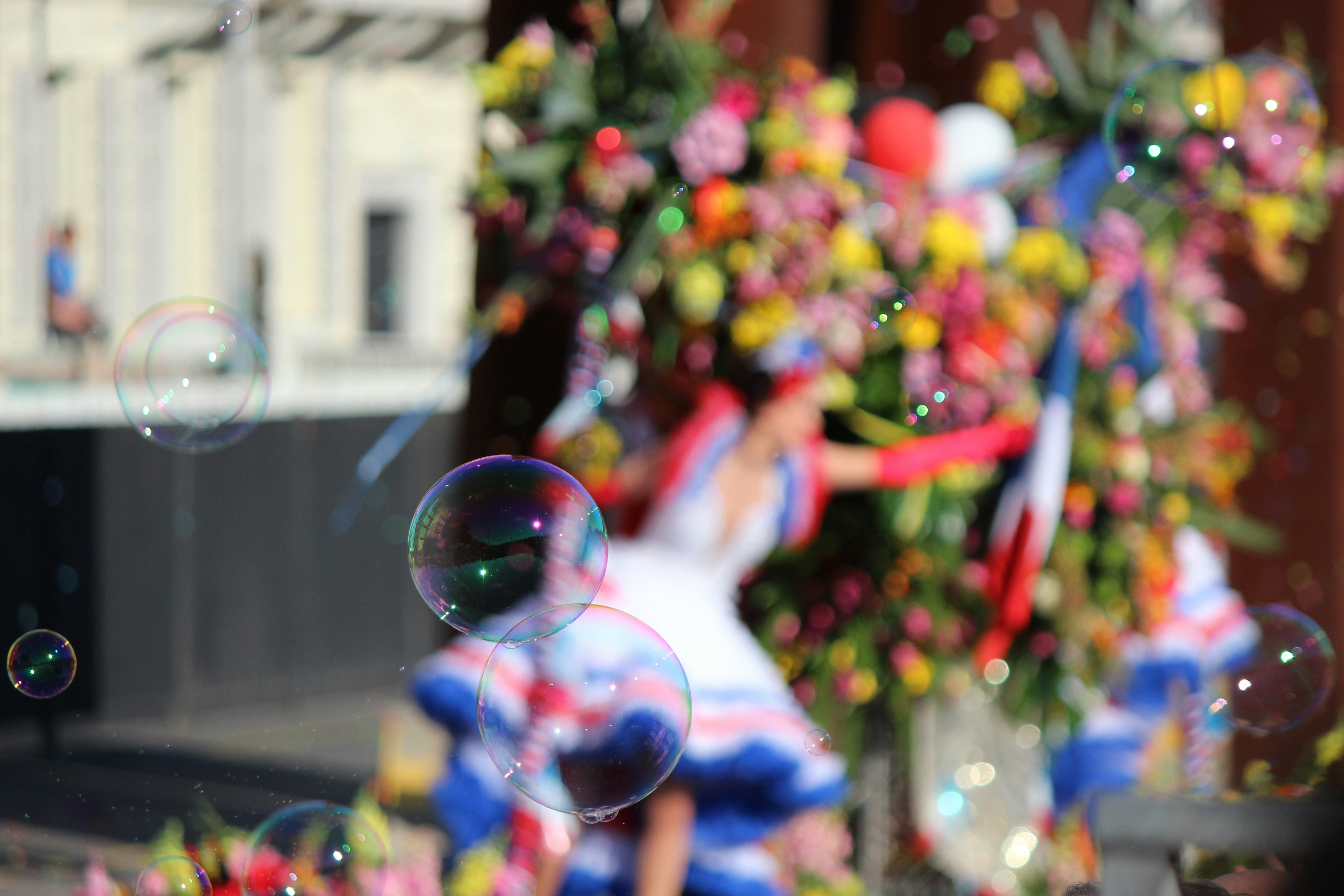 An blurred image of a colourful dancer with bubbles in focus in the foreground.