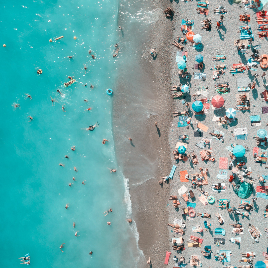 An aerial photograph of a busy, sandy beach with turquoise water.