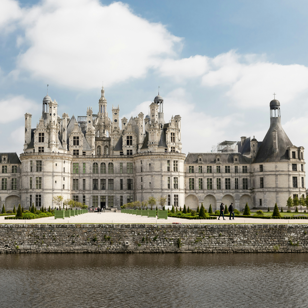 A giant white castle overlooking a lake.
