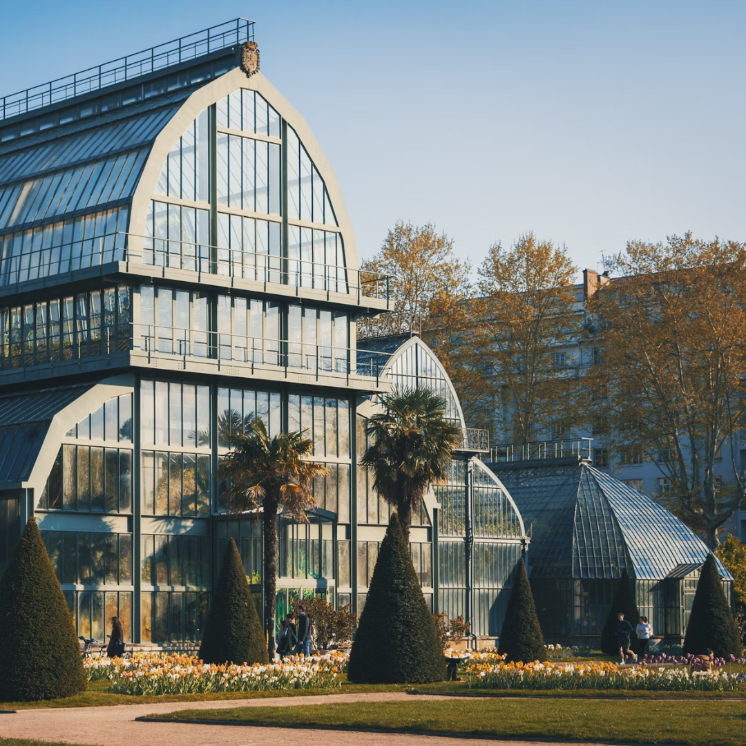 An image of the Parc de la Tete d'Or, showing an enourmous, multifloor greenhouse surrounded by garden.